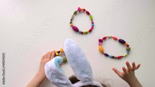 Top view of children hands is playing with color wreaths and eggs from the beads