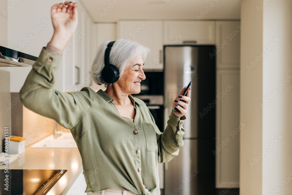 Happy senior woman dancing to her favourite music at home Happy senior woman dancing to her favourite music at home