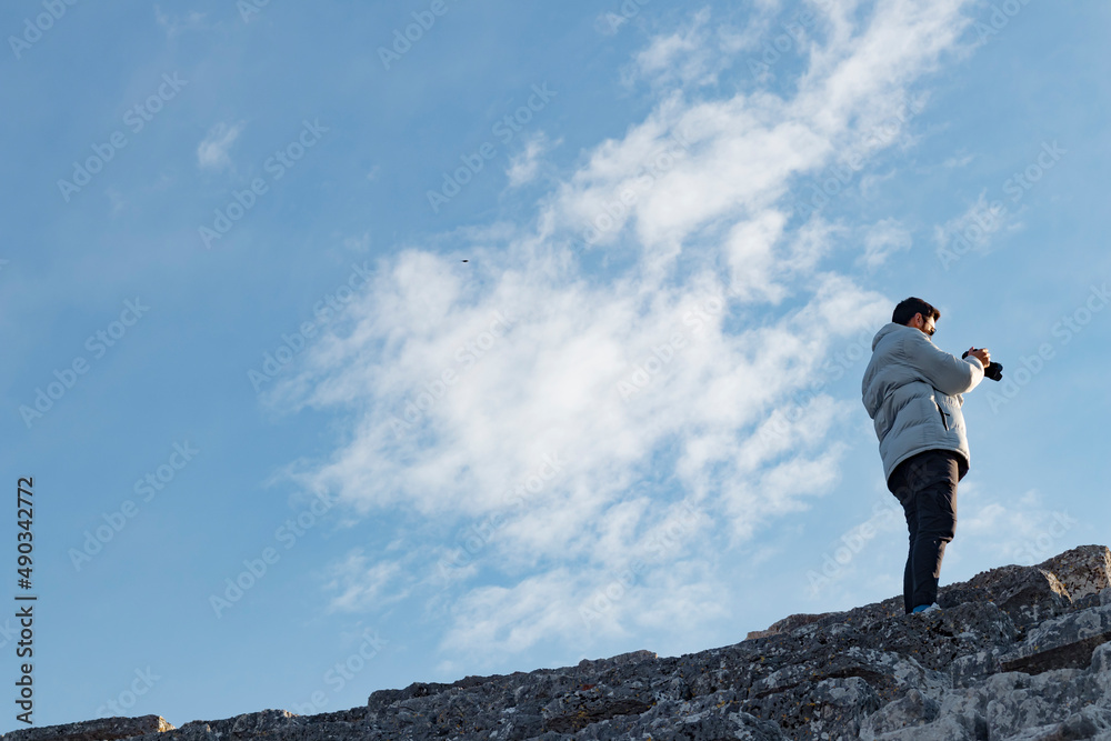 Back viev of young handsome man taking picture using camera. Beautiful blue sky. Wallpaper and web banner. Back viev of young handsome man taking picture using camera. Beautiful blue sky. Wallpaper and web banner.