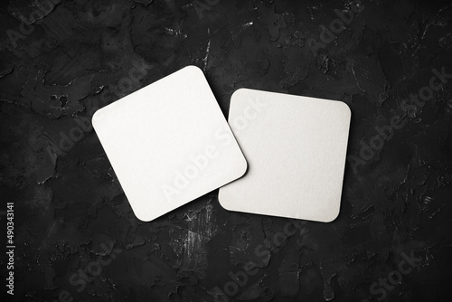 Photo of two blank white beer coasters on black stone background. Responsive design mockup. Flat lay. photo