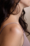 Closeup shot of unrecognizable tender young brunette woman's shoulder. Female body image, real skin, natural beauty.