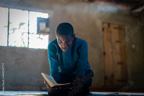 Photography African teenage boy sitting and reading book in poor school, high quality photo