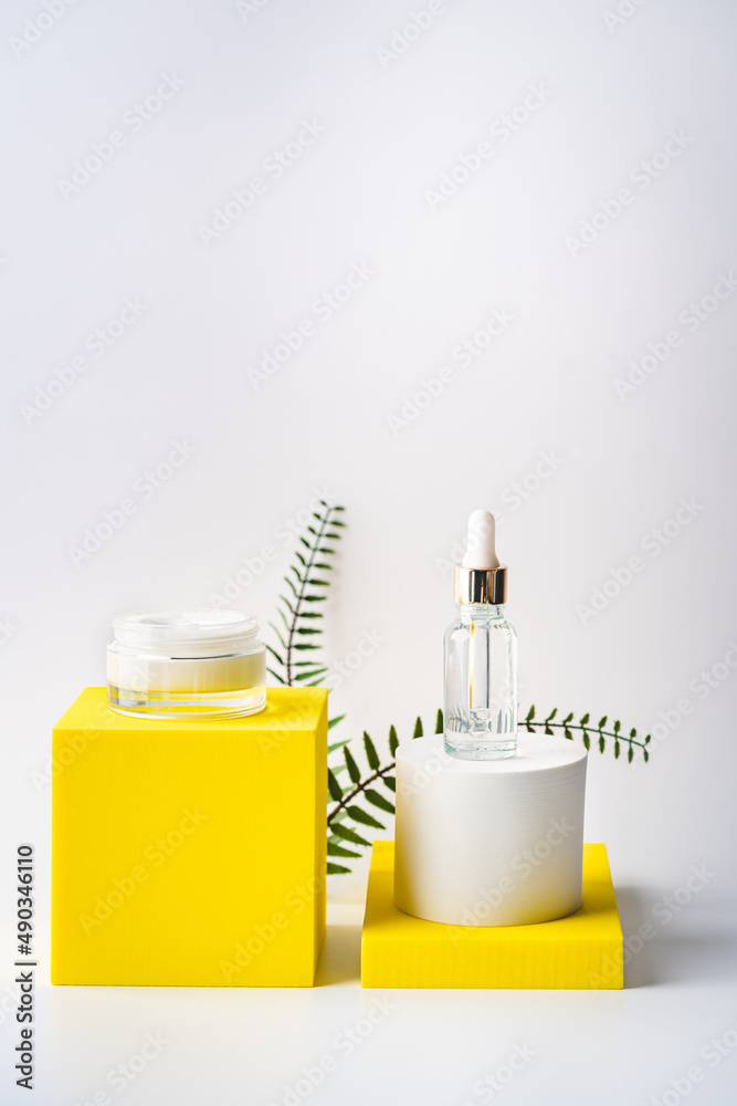 Glass cosmetic bottle with oil or serum and cream for skin care on special podium of yellow color. Natural skin care concept. Glass cosmetic bottle with oil or serum and cream for skin care on special podium of yellow color. Natural skin care concept.