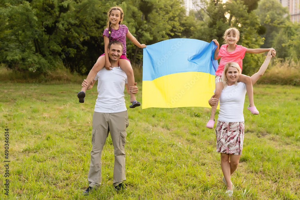 Fototapeta premium Happy family s with flag of Ukraine in field.