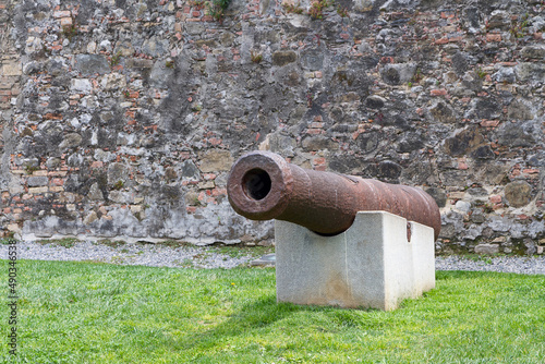 Ancient cannon on a concrete pedestal against a brick wall