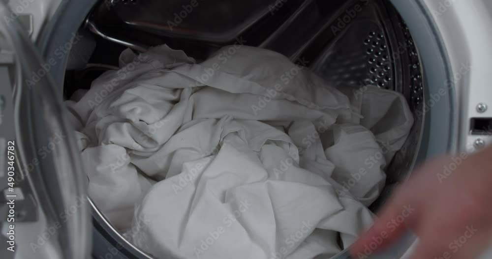 Close up static shot of hand putting laundry detergent into washing