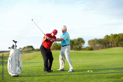 The correct technique. A male golfer getting help from his caddy on the golf course.