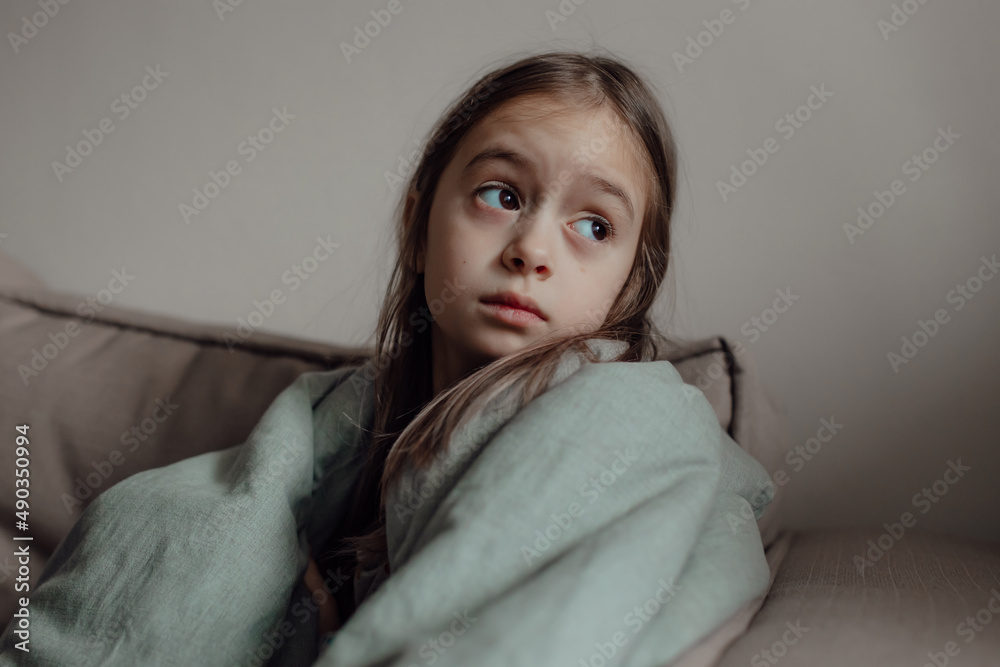 Ukrainian frightened child under a blanket. The girl is afraid of the sounds of air raids and explosions. Stop war. Pray for Ukraine. Ukrainian frightened child under a blanket. The girl is afraid of the sounds of air raids and explosions. Stop war. Pray for Ukraine.