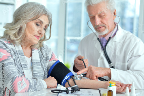 Portrait of elderly doctor measuring blood pressure