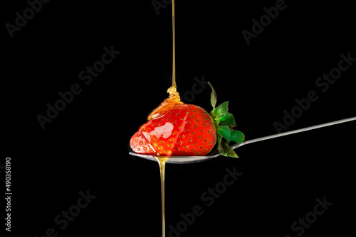 Φωτογραφία Delicious fresh strawberry on a spoon dipped in honey on a black background