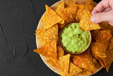 Trying some nachos or tortilla chips with guacamole sauce