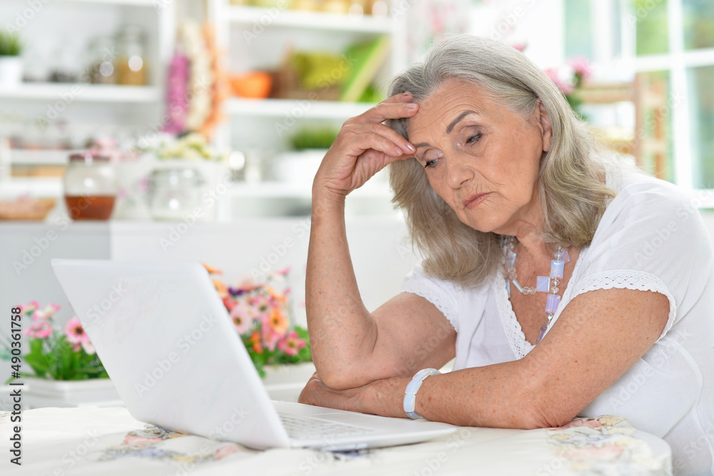 Portrait of tired senior woman using laptop