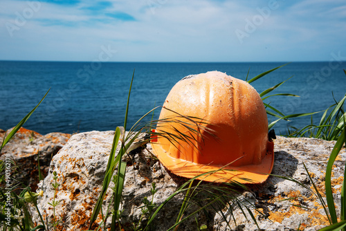 Construction helmet of a geologist on the background of a sea landscape. Excavations in the mountains.