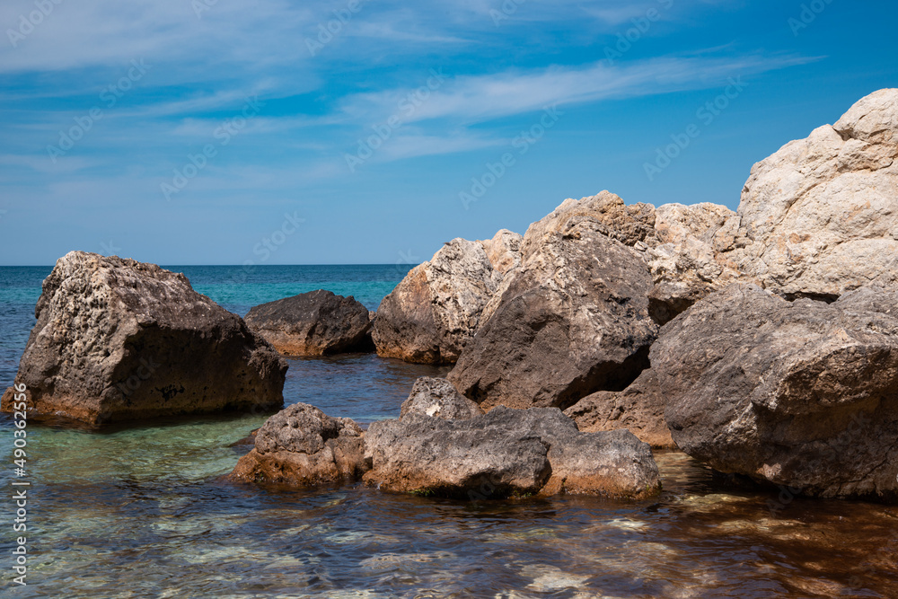 Summer seascape. Rocks and stones near the coastline. Blue sky and ocean.