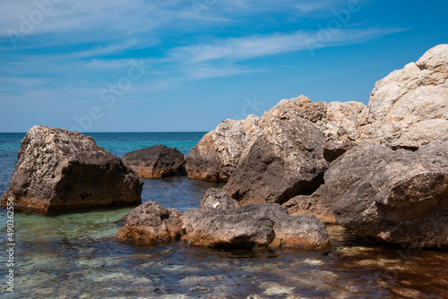 Summer seascape. Rocks and stones near the coastline. Blue sky and ocean. © Denis