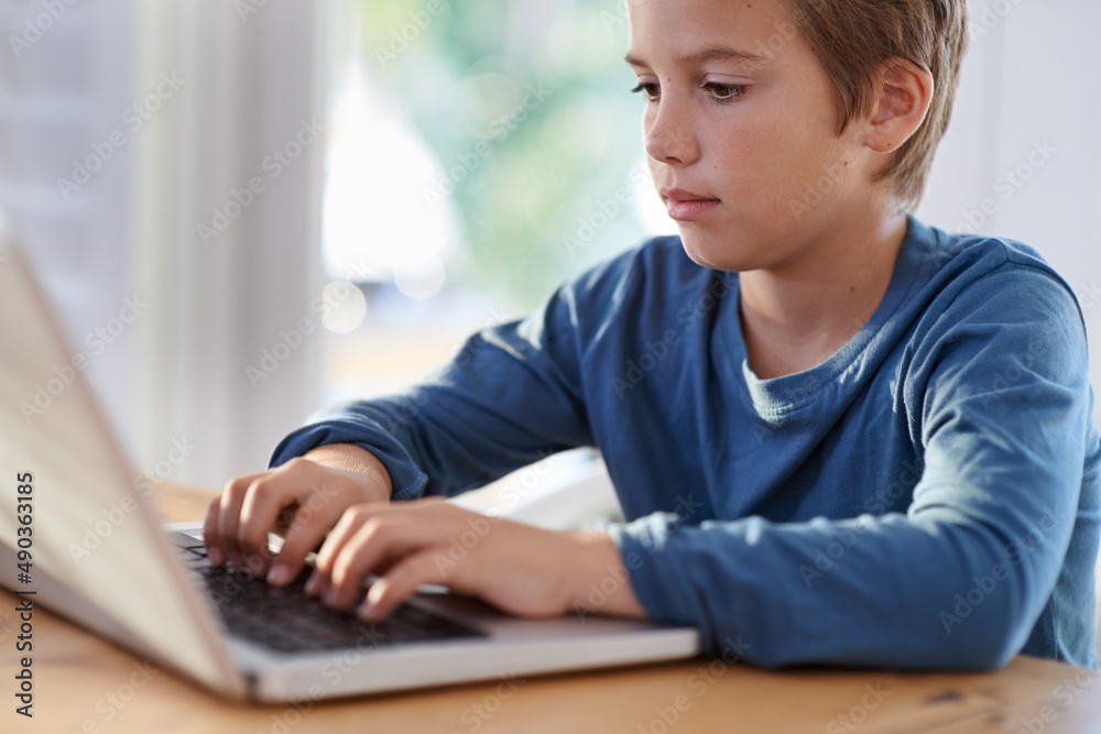 Getting his homework done in a flash. Shot of a young boy using a laptop at home. Getting his homework done in a flash. Shot of a young boy using a laptop at home.