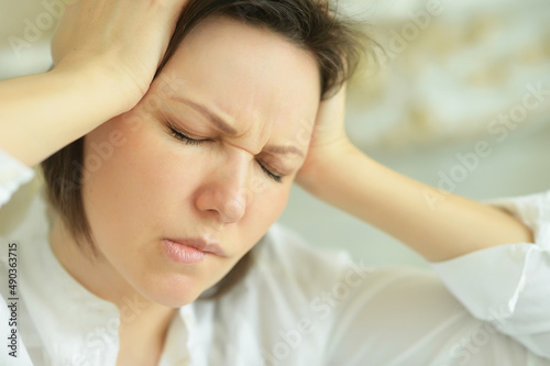 Portrait of young woman with headache posing at home