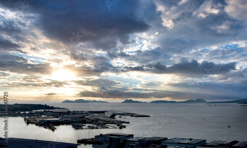 Vista general del puerto de Vigo y su ría con las Islas Cíes de fondo y cielo con nubes en claroscuro y tonos fríos al atardecer