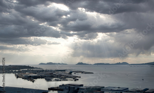 Vista general del puerto de Vigo y su ría con las Islas Cíes de fondo y cielo con nubes en claroscuro y tonos fríos al atardecer