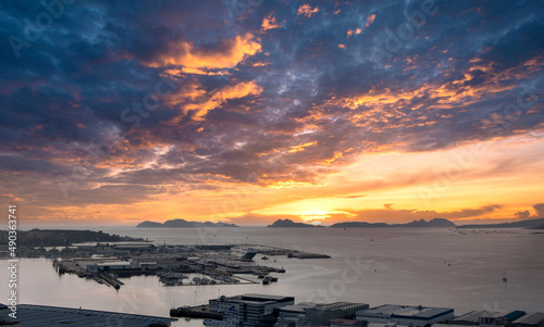 Vista general de Vigo y su Ría con la ciudad y el puerto, y las Islas Cíes de fondo con un cielo dramático y cálido al atardecer