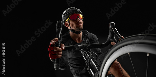 Fototapeta Naklejka Na Ścianę i Meble -  male cyclist riding road bicycle on black background