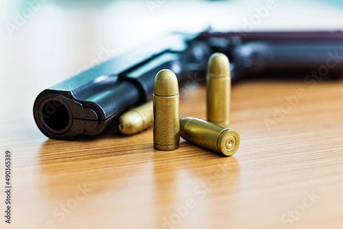 Gun with ammunition on wooden table