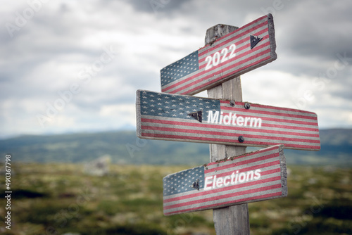 2022 midterm elections text quote on wooden signpost outdoors with the american flag on it. Politics and voting concept. photo
