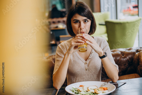 Young woman eating healthy breakfast with juice in a cafe