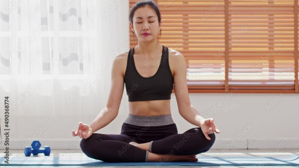 Calm of wellness Asian young woman sit on carpet breathing with yoga lotus pose,Yoga meditation of young healthy woman relax and comfortable at white cozy home,Yoga Exercise for Wellness Concept Calm of wellness Asian young woman sit on carpet breathing with yoga lotus pose,Yoga meditation of young healthy woman relax and comfortable at white cozy home,Yoga Exercise for Wellness Concept