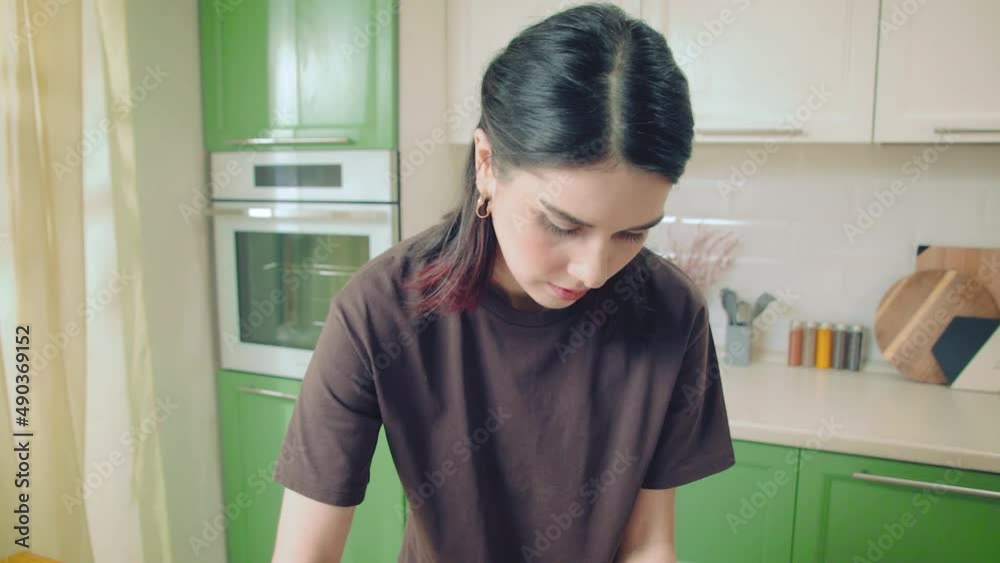 Young caucasian woman in brown t-shirt cooking at home kitchen. Hand held medium shot Young caucasian woman in brown t-shirt cooking at home kitchen. Hand held medium shot