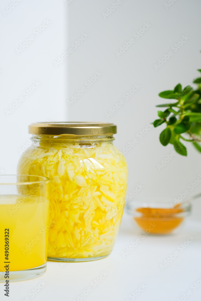 Fermented cabbage with turmeric. Cabbage kvass. Pickling vegetables without salt. Fermentation. Vitamin treatment and nutrition. Organic turmeric powder and green leaves of houseplant in a frame. Fermented cabbage with turmeric. Cabbage kvass. Pickling vegetables without salt. Fermentation. Vitamin treatment and nutrition. Organic turmeric powder and green leaves of houseplant in a frame.