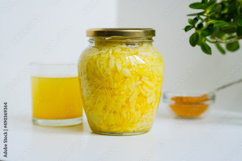 Fermented cabbage with turmeric. Cabbage kvass. Pickling vegetables without salt. Fermentation. Vitamin treatment and nutrition. Organic turmeric powder and green leaves of houseplant in a frame. Fermented cabbage with turmeric. Cabbage kvass. Pickling vegetables without salt. Fermentation. Vitamin treatment and nutrition. Organic turmeric powder and green leaves of houseplant in a frame.