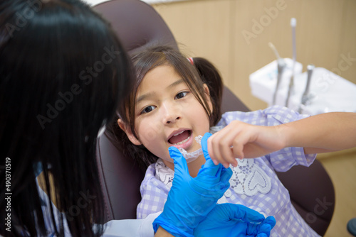 Female dentist showing invisalign to a little girl in dental clinic, teeth check-up and Healthy teeth concept
