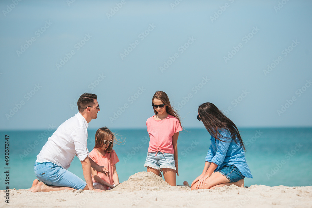 Family of four making sand castle at tropical white beach Family of four making sand castle at tropical white beach