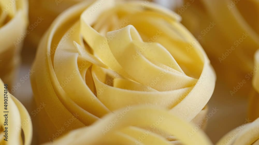 Uncooked noodle nest . Slow motion video.slow motion pasta dry tagliatelle spin on the table. On a black background.view from above Uncooked noodle nest . Slow motion video.slow motion pasta dry tagliatelle spin on the table. On a black background.view from above