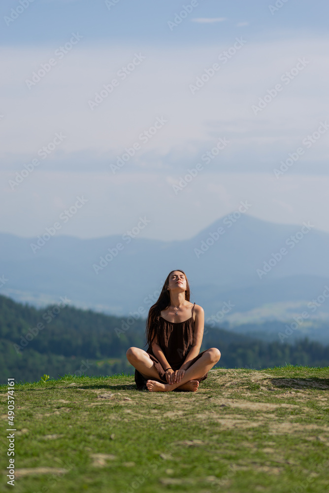 Female sitting in pose of lotus in mountains.