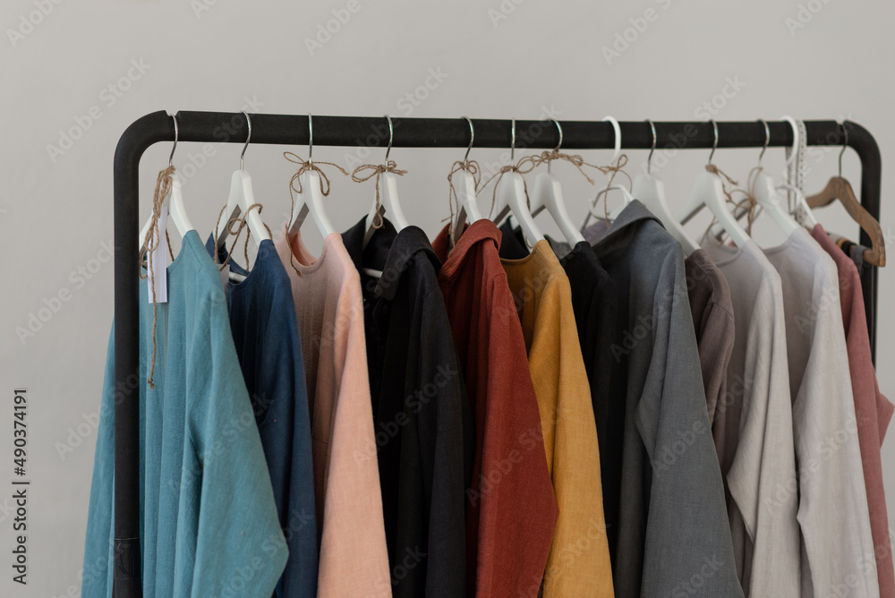 Black minimalistic rack with eco linen clothes on white background Black minimalistic rack with eco linen clothes on white background