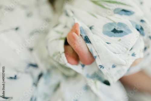 Foto Newborn baby feet sticking out of muslin blanket with blue poppies