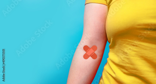 Blood donation. Blood donor woman in yellow T-shirt with patch bandage after giving blood on a blue background. World blood donor day and save life concept.