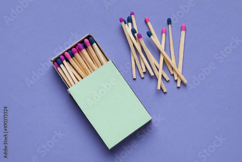 Box with different new matchsticks on purple background photo