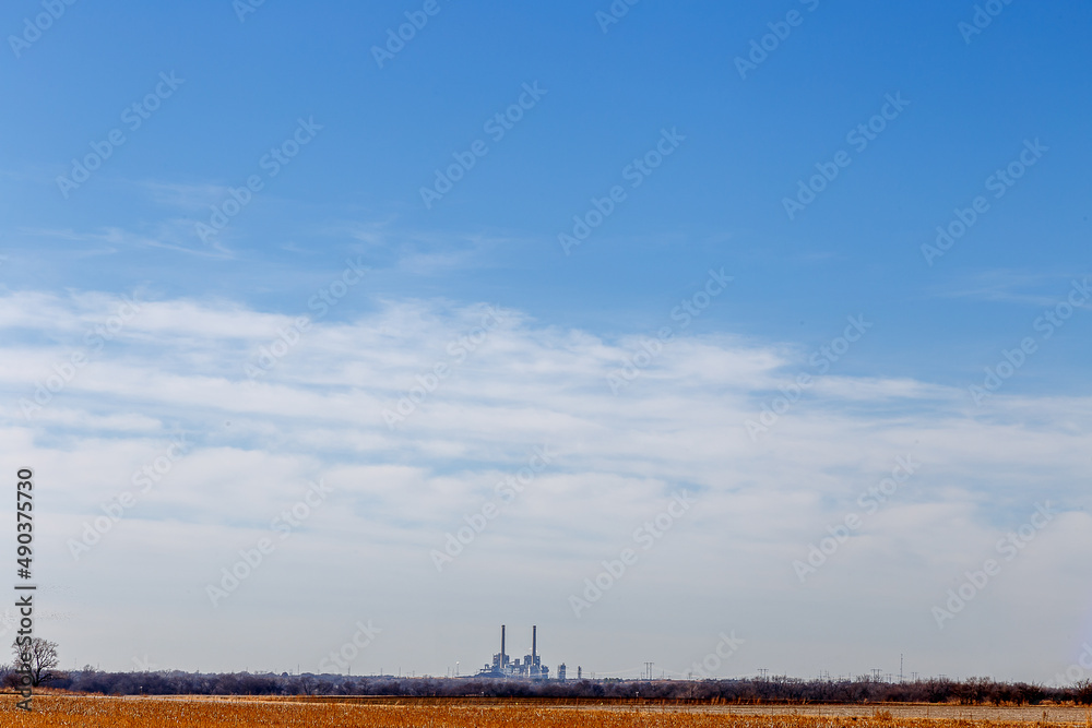 A Harvested Field and a Coal Electric Plant Against a Big Blue Sky