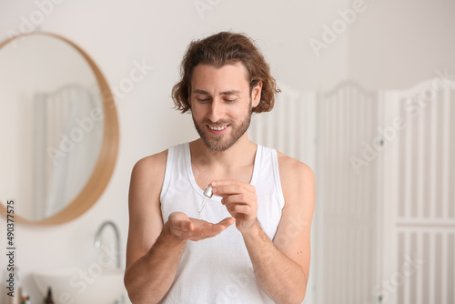 Young man using serum for s...