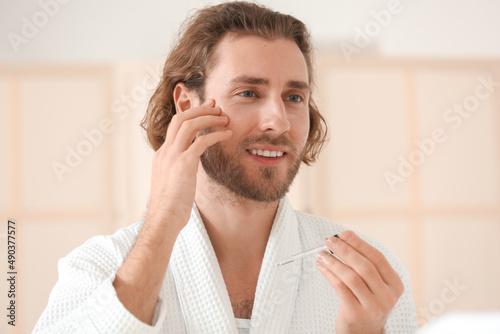 Young man using serum for s...