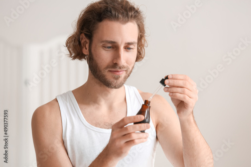 Young man using serum for s...