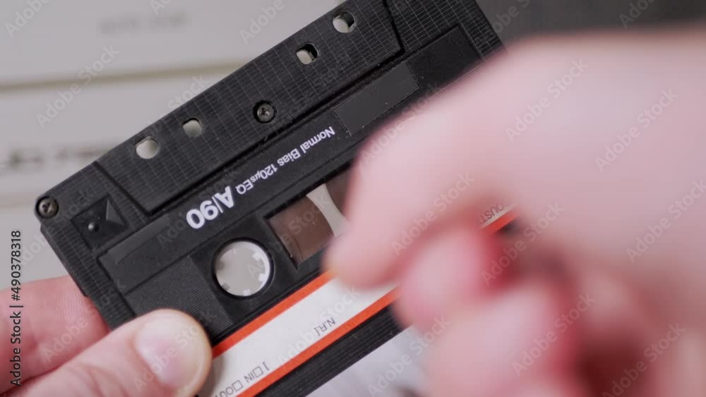 Female Rewinds a Magnetic Tape with Finger on Old Vintage Audio Cassette. Process rewinding a jammed tape manually. Classic black retro cassette 90s for listening to music on a player, tape recorder. Female Rewinds a Magnetic Tape with Finger on Old Vintage Audio Cassette. Process rewinding a jammed tape manually. Classic black retro cassette 90s for listening to music on a player, tape recorder.