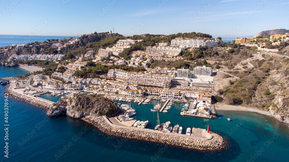 Aerial perspective of La Herradura city, Granada, Spain. Beautiful coastal city situated in south of Spain. View of the port and luxury urbanisation on hills. Mountains in background. Real Estate