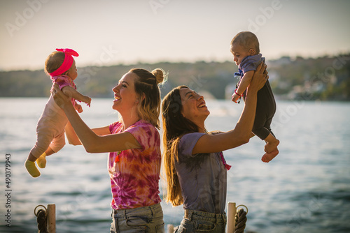 Two Moms with their babies playing by the lake on a sunny afternoon photo