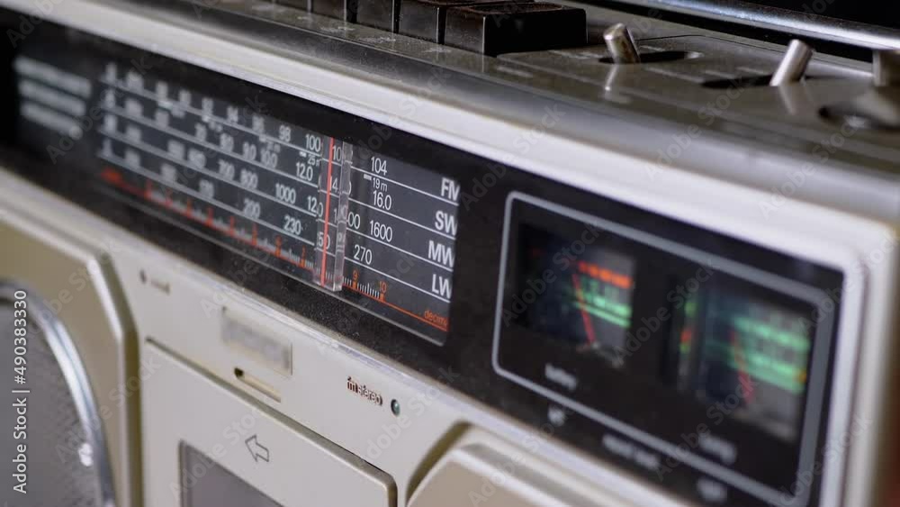 Tuning the Frequency, Searching Wave on an Old Vintage Analog Radio. Search for a music radio station on a dial scale on panel of a short-wave portable FM receiver, player, tape recorder 80s, 90s. Tuning the Frequency, Searching Wave on an Old Vintage Analog Radio. Search for a music radio station on a dial scale on panel of a short-wave portable FM receiver, player, tape recorder 80s, 90s.
