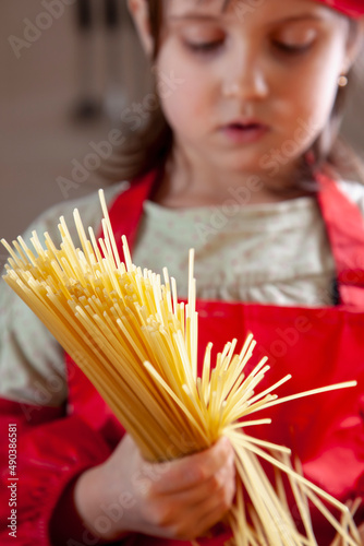 Beautiful caucasian child girl chef praparing vermicelli. Cooking process and food concept. photo