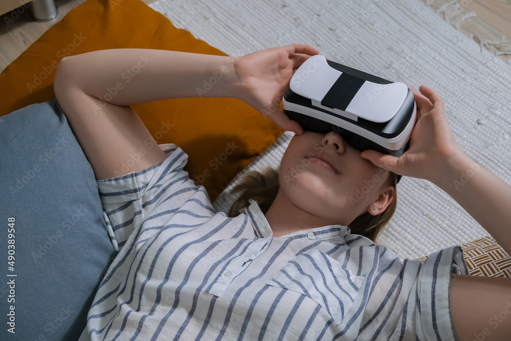 VR relax.European girl using virtual reality to relax and de-stress at home. Girl wearing virtual reality vr glasses relaxes in a virtual environment wellness, mental health immersive reality VR relax.European girl using virtual reality to relax and de-stress at home. Girl wearing virtual reality vr glasses relaxes in a virtual environment wellness, mental health immersive reality